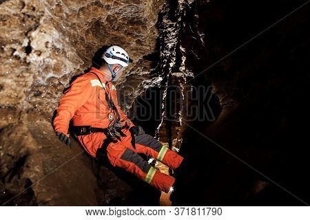 Speleologist Descend By The Rope In The Deep Vertical Cave Tunnel.
