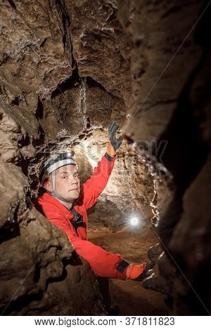 Man Walking And Exploring Dark Cave With Light Headlamp Underground.