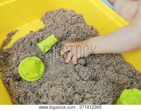A Child Plays With Kinetic Sand: Closeup Of A Child's Hand And Sand. Educational Games With Children