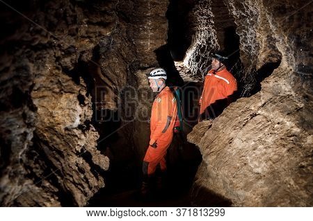 Two Men, Strong Physique, Explore The Cave. Men Dressed In Special Clothes To Pass Through The Cave 
