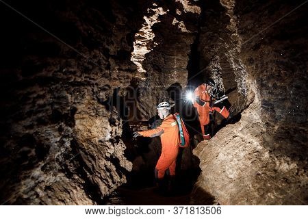 Two Men, Strong Physique, Explore The Cave. Men Dressed In Special Clothes To Pass Through The Cave 