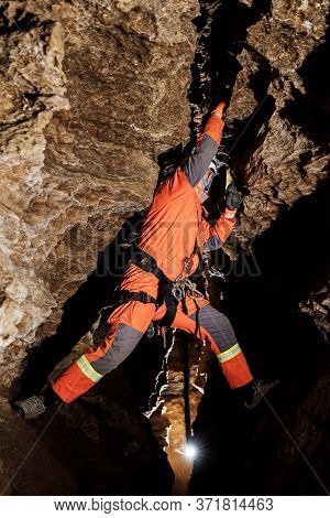 Speleologist Descend By The Rope In The Deep Vertical Cave Tunnel.