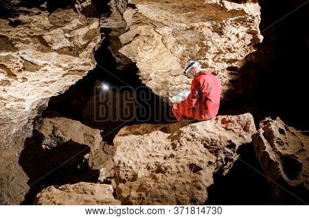 Man Walking And Exploring Dark Cave With Light Headlamp Underground.