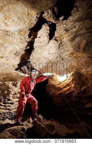 Man Walking And Exploring Dark Cave With Light Headlamp Underground.