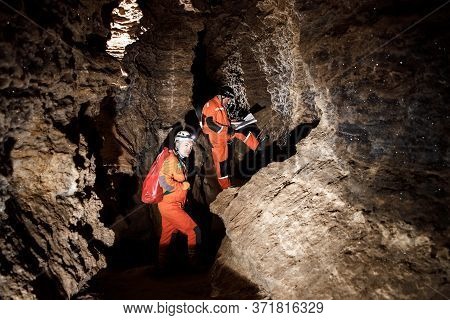 Two Men, Strong Physique, Explore The Cave. Men Dressed In Special Clothes To Pass Through The Cave 