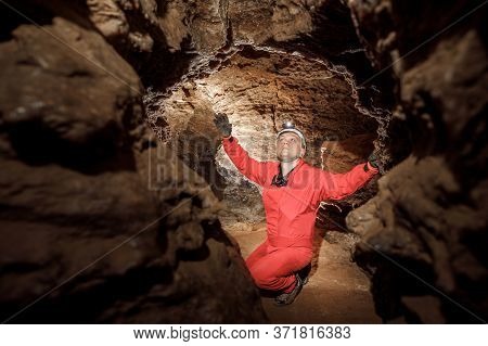 Man Walking And Exploring Dark Cave With Light Headlamp Underground.