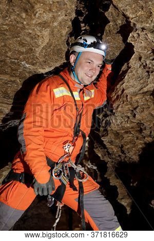 Speleologist Descend By The Rope In The Deep Vertical Cave Tunnel.