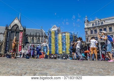 Amsterdam, Netherlands - July 02, 2018: Children Catch Soap Bubbles In The Central Dam Square In Ams