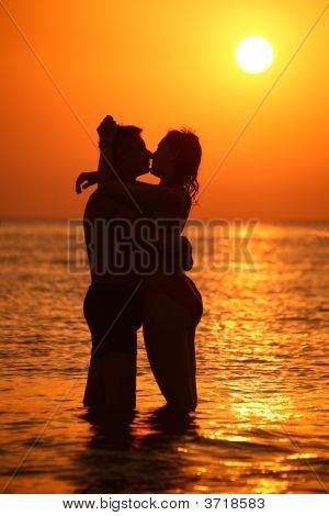 Silhouette couple Ebraces et baisers en mer sur coucher de soleil