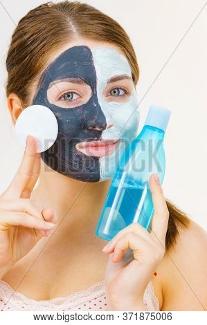Woman With Clay Carbo Black Mask On One Half Face And White Mud On Second Half. Girl Removing Cosmet