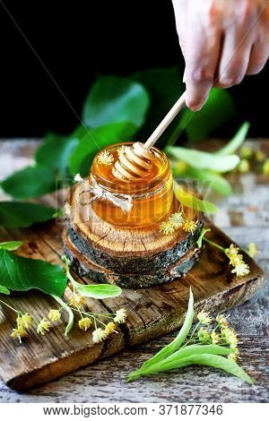 Selective Focus. Macro. Stick For Honey With Linden Honey. Linden Honey In A Jar. Leaves And Flowers