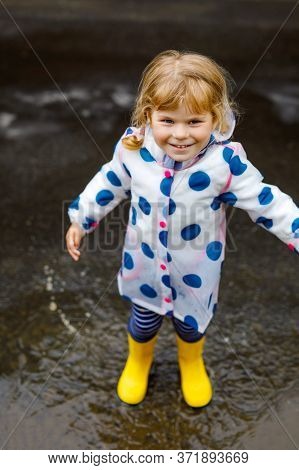 Little Toddler Girl Wearing Yellow Rain Boots, Running And Walking During Sleet On Rainy Cloudy Day.