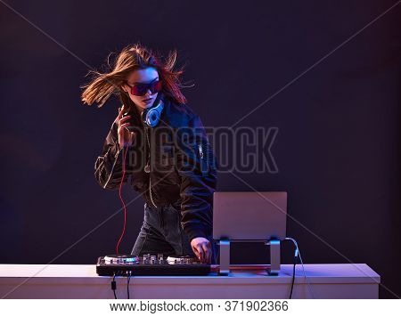 Stylish Dj Girl With Headphones And Glasses On The Bomber Jacket Mixes The Music At The Party And Ne