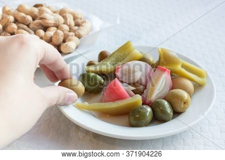 A Hand Picking An Olive From A Plate