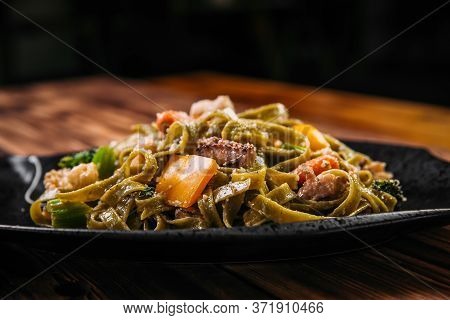 Closeup Side View On Spinach Fettuccine Pasta With Beef And Vegetables On The Wooden Table, Horizont