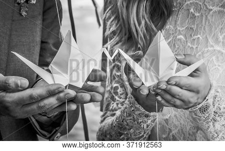 Paper Cranes Kiss In The Palms Of Men And Women. Origami For Decoration Of The Wedding.