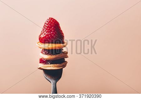 Trendy Home Breakfast With Tiny Cereal Pancakes And Fresh Strawberries On The Fork, Pink Background