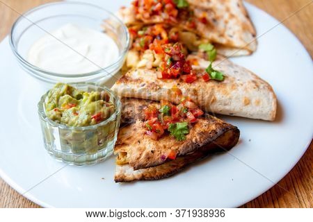 Delicious Mexican quesallidas made with chicken, tomato pieces and served with guacamole sauce.
