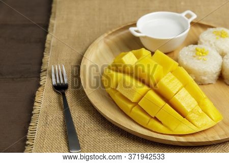 Close Up Yellow Half  Mango With Small Fork. Mango Fruit Cubes On The Wooden Table. Tropical Fruit A