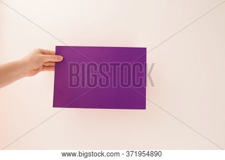 Hands Of Young Woman Holding Blank Purle Sheet Of Paper For Text And Design, Mock Up On Light Backgr