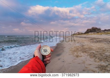 First-person View Of A Female Hand With A Compass On A Background Of A Beautiful Sea Landscape. The 