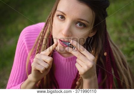 Close-up Outdoors Portrait Of Young Female Shaman In Pink Knitted Sweater With Long Dreadlocks Playi