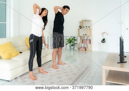 Young Asian Couple Doing High-intensity Interval Training Together And Looking Tv At Home, Man And W