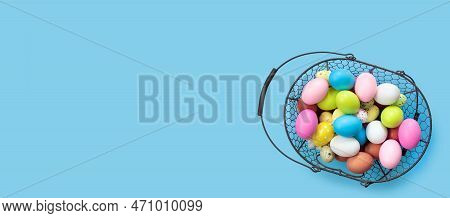 Metal Basket With Multicolored Painted Easter Eggs On Blue Paper Background. Flat Lay  Top View With