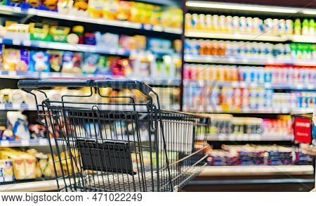 A Shopping Cart By A Store Shelf In A Supermarket