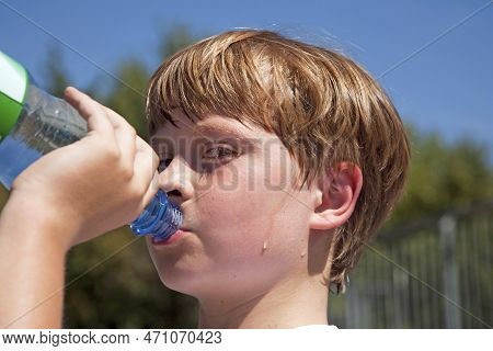 Boy Is Sweating And Thursty From Doing Sports And Drinks Mineral Water Out Of A Bottle