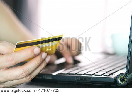 Young Man Sat In The Living Room On Sofa , Using His Computer  And Holding Credit Card Her Online To