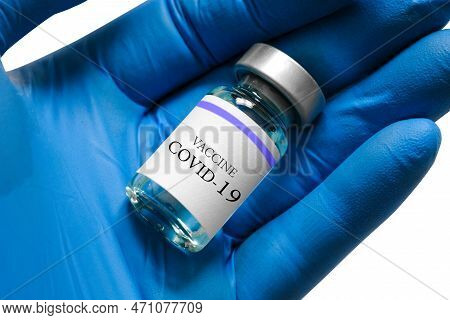 Doctor's Hand Holds A Syringe And A Blue Vaccine Bottle At The Hospital. Health And Medical Concepts