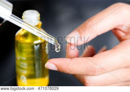 Hands Of A Beautiful Woman Dropping Serum Collagen Moisturizer Of Face Into Clear Yellow Bottle Soft
