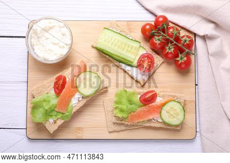 Tasty Crispbreads With Salmon, Cream Cheese, Cucumber And Tomato On White Wooden Table, Top View
