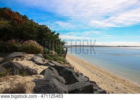 Nassau Point Beach With Large Boulders And Thick Green Brush Protecting The Land From The Water.