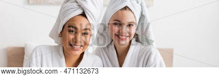 Young And Positive Multiethnic Women In Soft Terry Robes And Towels Looking At Camera In Bedroom, Ba