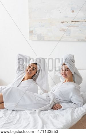 Young And Pretty Interracial Women In White Soft Robes And Towels Smiling At Camera While Resting On