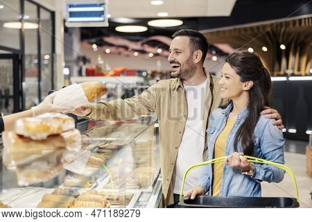 Couple Is Purchasing Bread At Bakery Section In Supermarket.