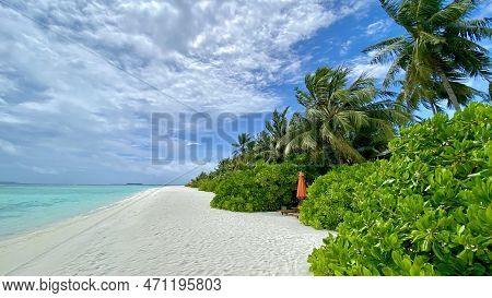 Paradise And Empty Beach With White Sand, Beach Chair And Closed Umbrella Clear Blue Water And Blue 