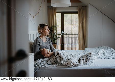 Mother Brestfeeding Her Little Newborn Baby In Their Bedrooom.