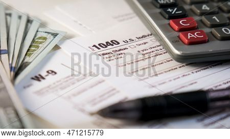 Close Up Shot Of A 1040 And W9 Individual Tax Form Are Placed On Desk Of American Citizen.