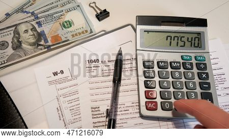 Top View Of Calculate The Amount On A Calculator 1040 And W9 Individual Tax Form Are Placed On Desk 
