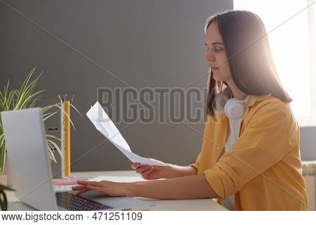 Portrait Of Young Adult Dark Haired Woman Manager Sitting At Her Workplace And Working With Document