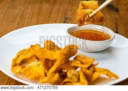 Using Chopsticks Clamp A Delicious Homemade Crispy Deep Fried Wonton In White Ceramic Dish Dipping I