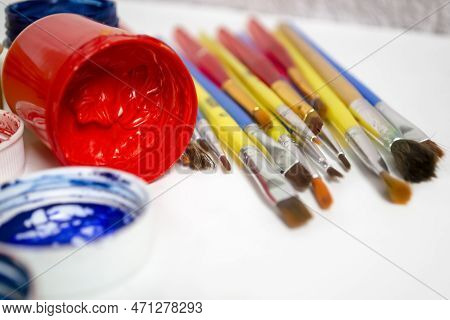 Jars Of Colored Paint Stand Next To The Brushes. For Artists, There Are A Lot Of Paints And Brushes.