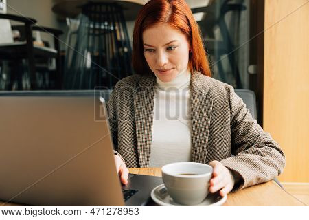 Businesswoman Working In A Coffee Shop In The Morning. Female With Ginger Hair In Formal Wear Typing