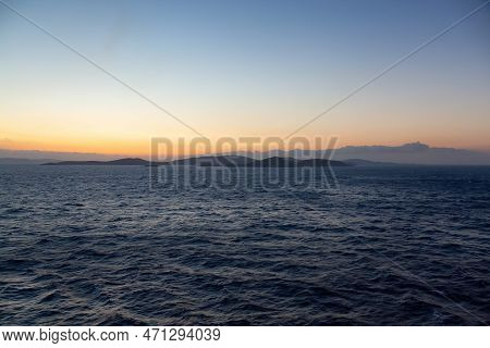 Rocky Island On Mediterranean Sea. Rinia Near Mikonos, Greece, Europe. Nature Background. Sunrise Sk