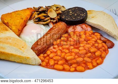 White Board With Full English Breakfast With Bacon, Fried Egg, Beans, Tomato, Roasted Sausage, Black