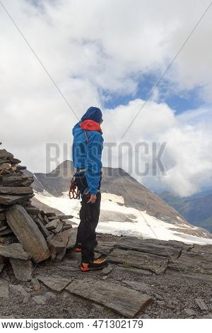 Mountaineer (man) Standing Next To Cairn On Summit Of Eiswandbichl And Looking At Mountain Snow And 