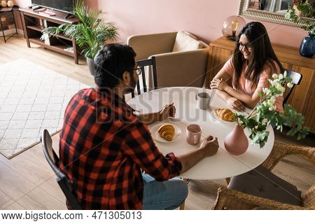Young Diverse Loving Couple Eating Croissant And Talks Together At Home In Breakfast Time. Communica